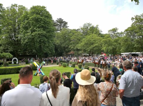 Rennbahnbesucher betrachten die Pferde am Führring