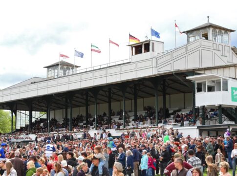 Pferde und Jockeys zwischen den Zuschauermassen vor der Tribüne in Köln