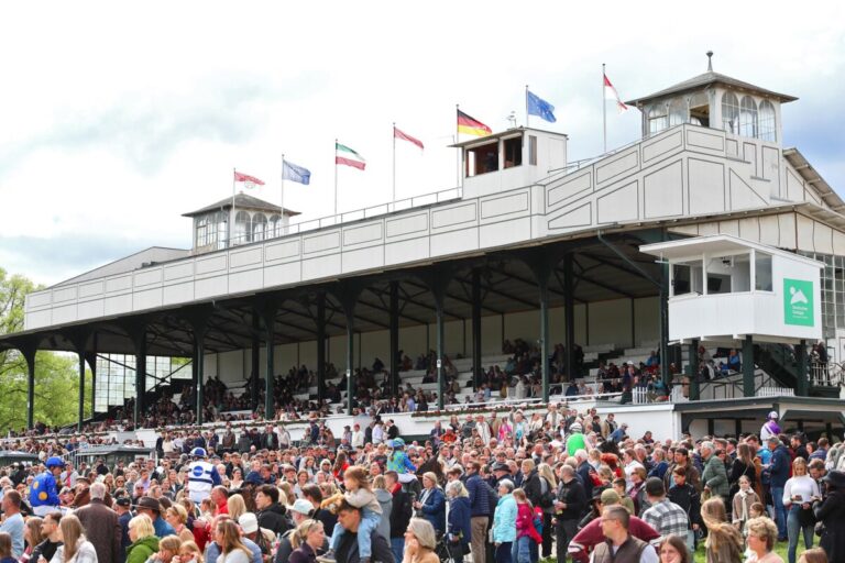 Pferde und Jockeys zwischen den Zuschauermassen vor der Tribüne in Köln